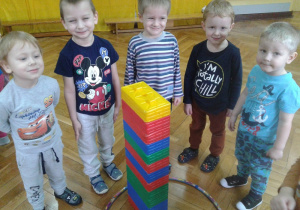 Piątka chłopców z młodszej grupy stoi przy zbudowanej przez siebie wieży z klocków